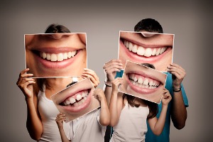 Family holding up pictures of smiles Dental Care Bloomington IL