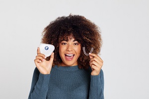 Woman holding up Teeth Aligners and case in Bloomington IL