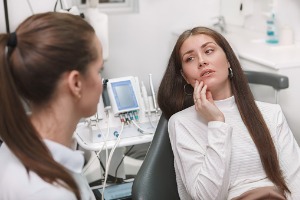 A patient holds her jaw as she considers Bonding Dentistry in Normal, IL