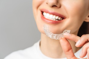 A woman smiles while holding a tray from her Take Home Whitening in McLean County IL