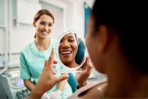 A woman smiles into a mirror after her checkup at Cottage Dental Care, a Bloomington IL Dental Office.