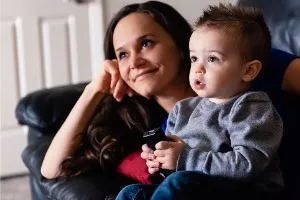 A mother and her son watch a TV show about going to the dentist to prep for his first dentist appointment