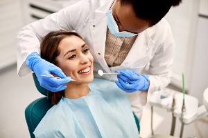 A woman who is concerned about how oral health affects the body smiles while her dental hygienist works on her teeth